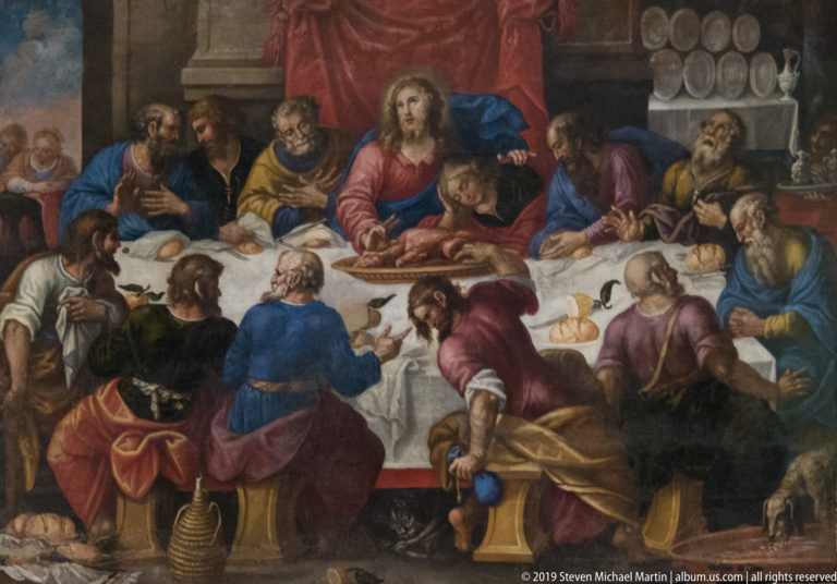 Religious painting of Christ seated at the center of a table surrounded by apostles in colorful robes.