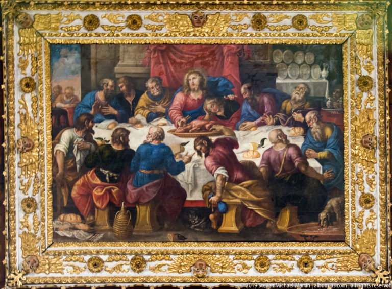 Last Supper painting with Christ and apostles at a table, surrounded by a broad ornate gilded frame.