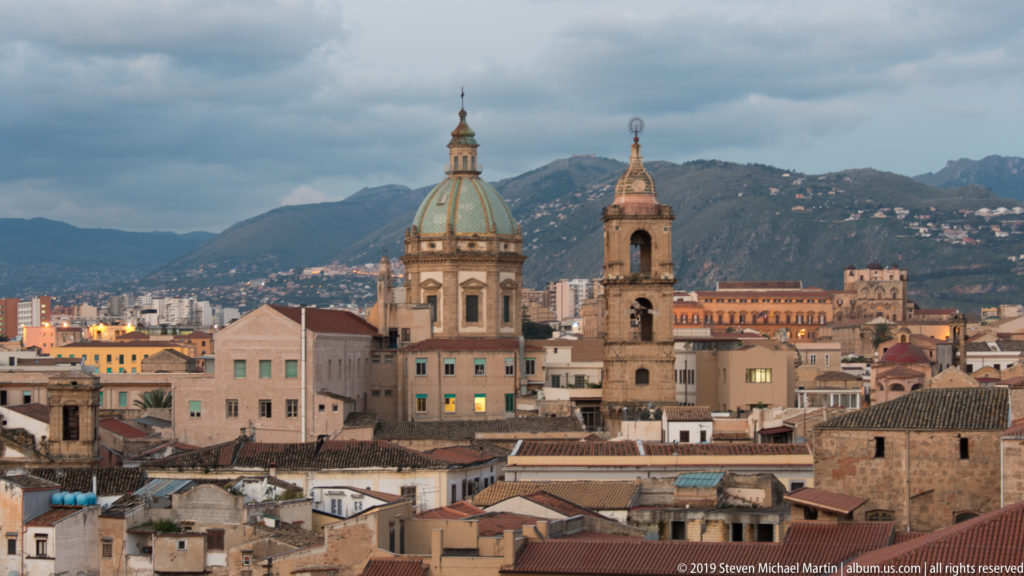 Two domes and a slender bell tower rise above Palermo’s rooftops before Monte Pellegrino.
