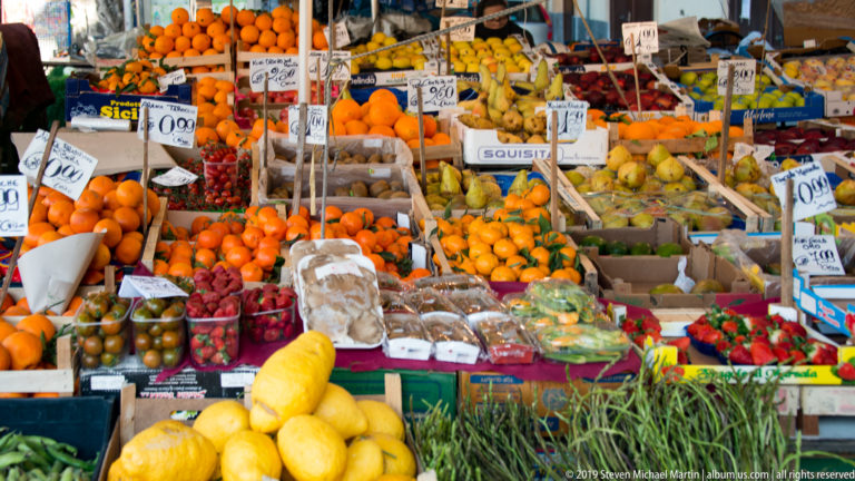 Lemons and oranges fill a market display beneath handwritten price cards in Palermo.