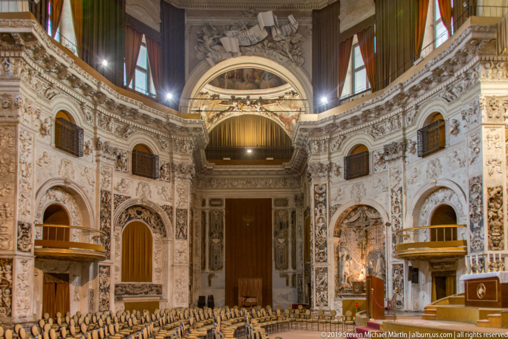 A central aisle runs through a richly decorated church nave toward the altar.