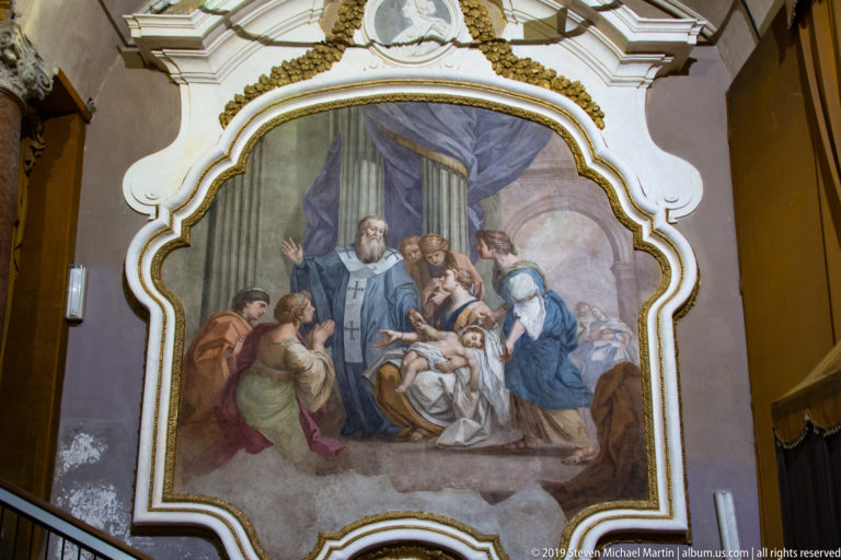 A framed Last Supper painting hangs within an ornate church interior in Palermo.