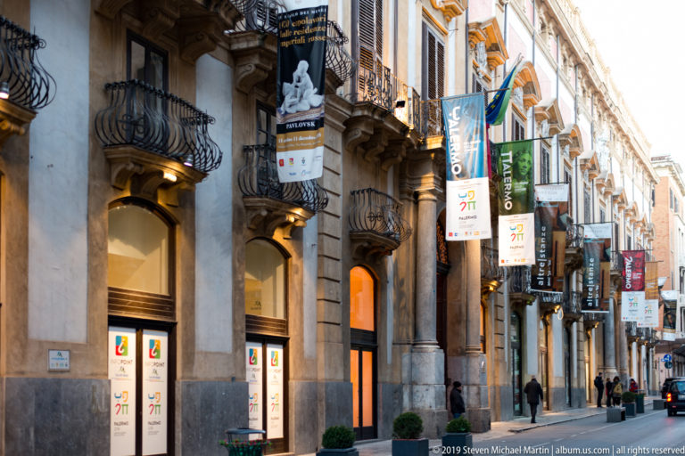 Balconies and projecting shop signs line a narrow street in Palermo’s historic center.