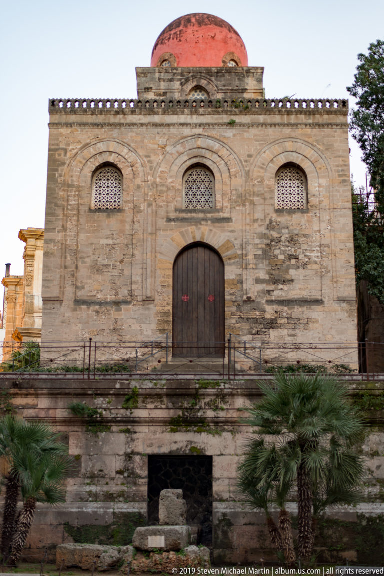 The front façade of San Cataldo shows a central door, three arched windows and its red dome.