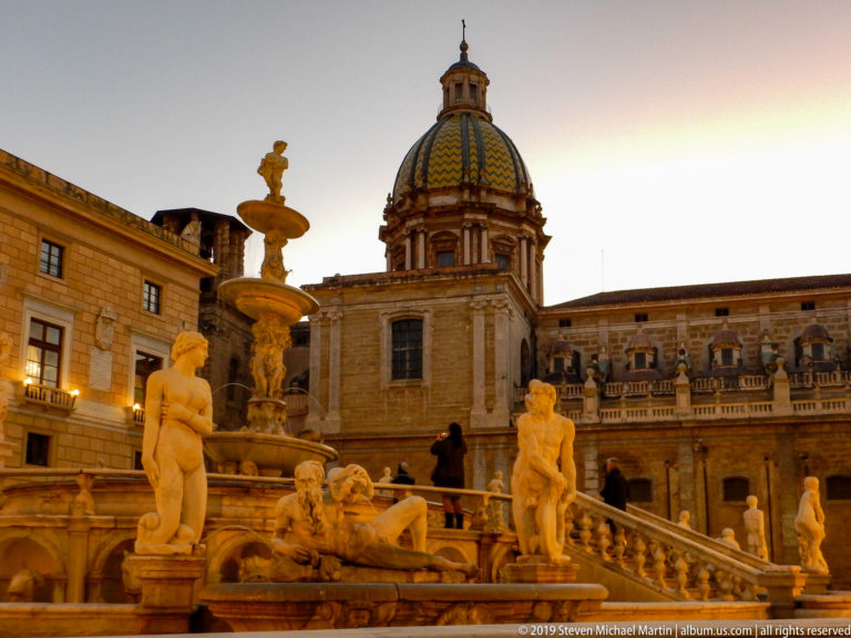 Fontana Pretoria statues frame the dome and upper façade of San Cataldo across the square.