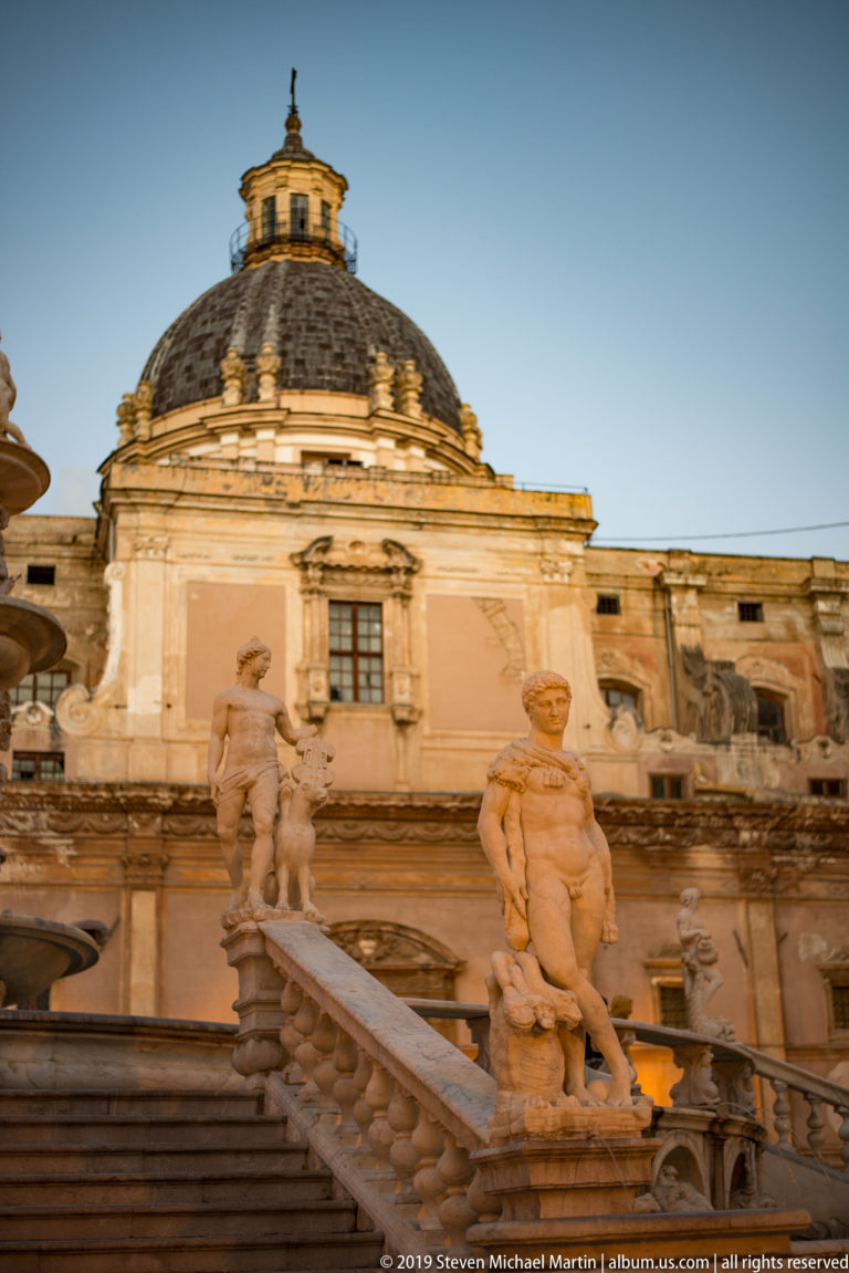 Fountain figures in Piazza Pretoria are framed below the red dome of San Cataldo.