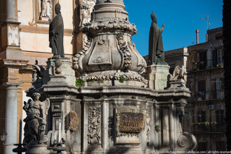 Carved figures and scrollwork decorate a projecting stone bay on a Palermo church.