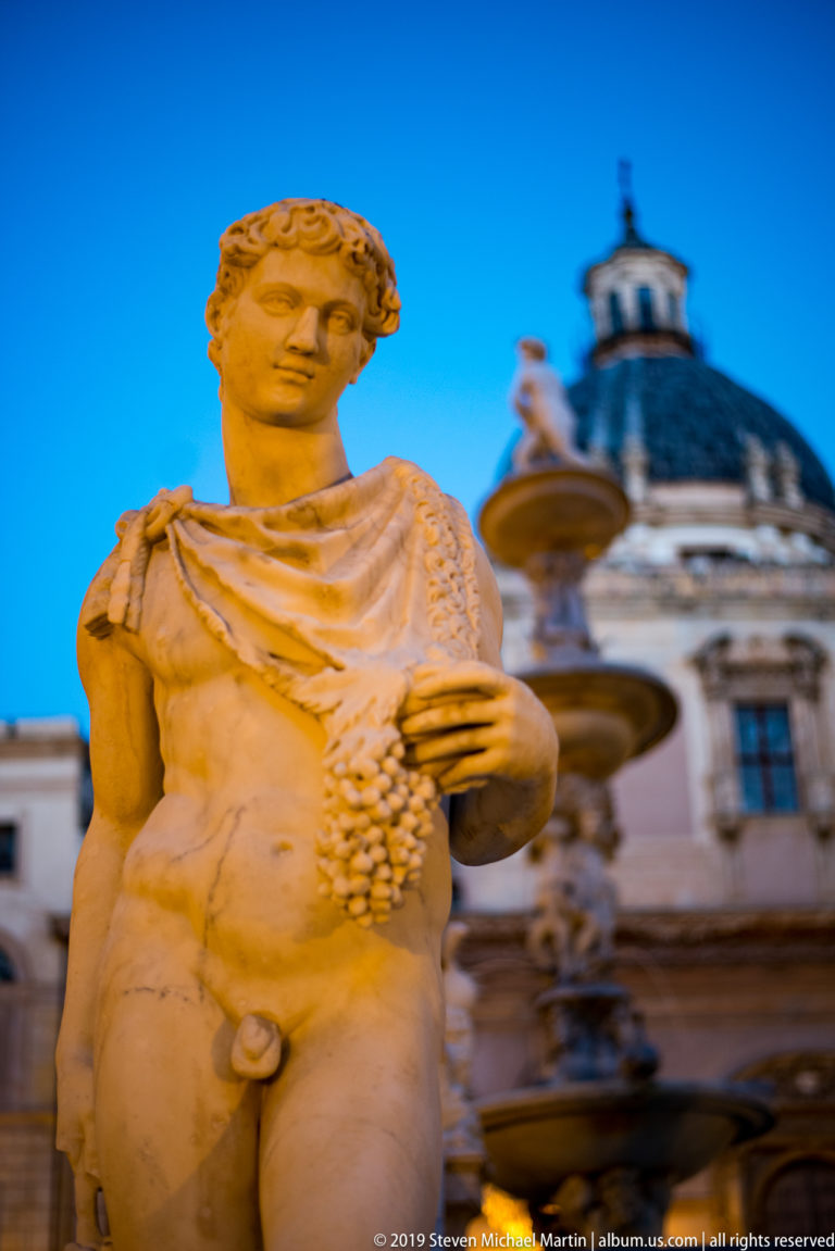 A reclining marble male figure from Fontana Pretoria fills the foreground, with a basin and domed roof behind.