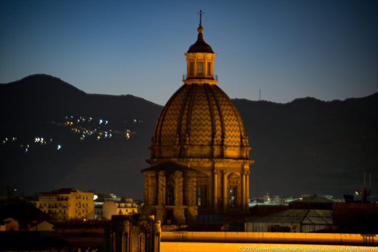 A gold-lit patterned dome and lantern stand alone against Palermo’s dark night sky.