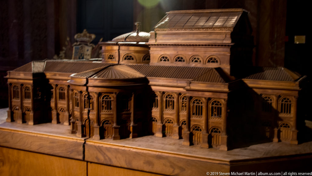 Wooden architectural model of Teatro Massimo showing the portico, side wings, rooflines, and tall stage-house block.