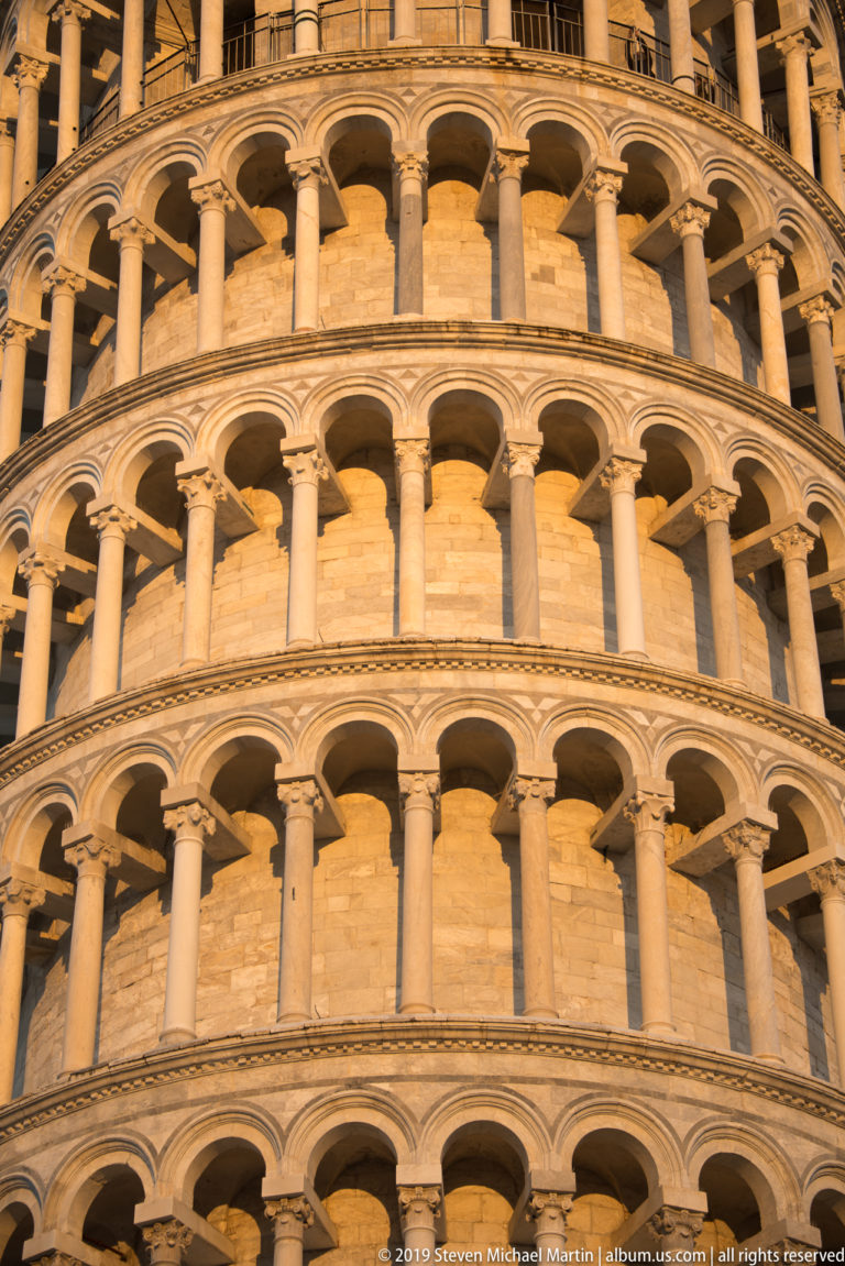 Close upward view of repeated marble columns and round-arched loggias on the Leaning Tower of Pisa.
