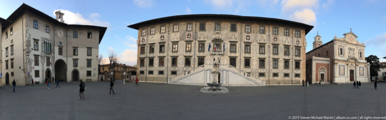 Ornamented Palazzo della Carovana façade and monumental staircase seen across Piazza dei Cavalieri in Pisa.