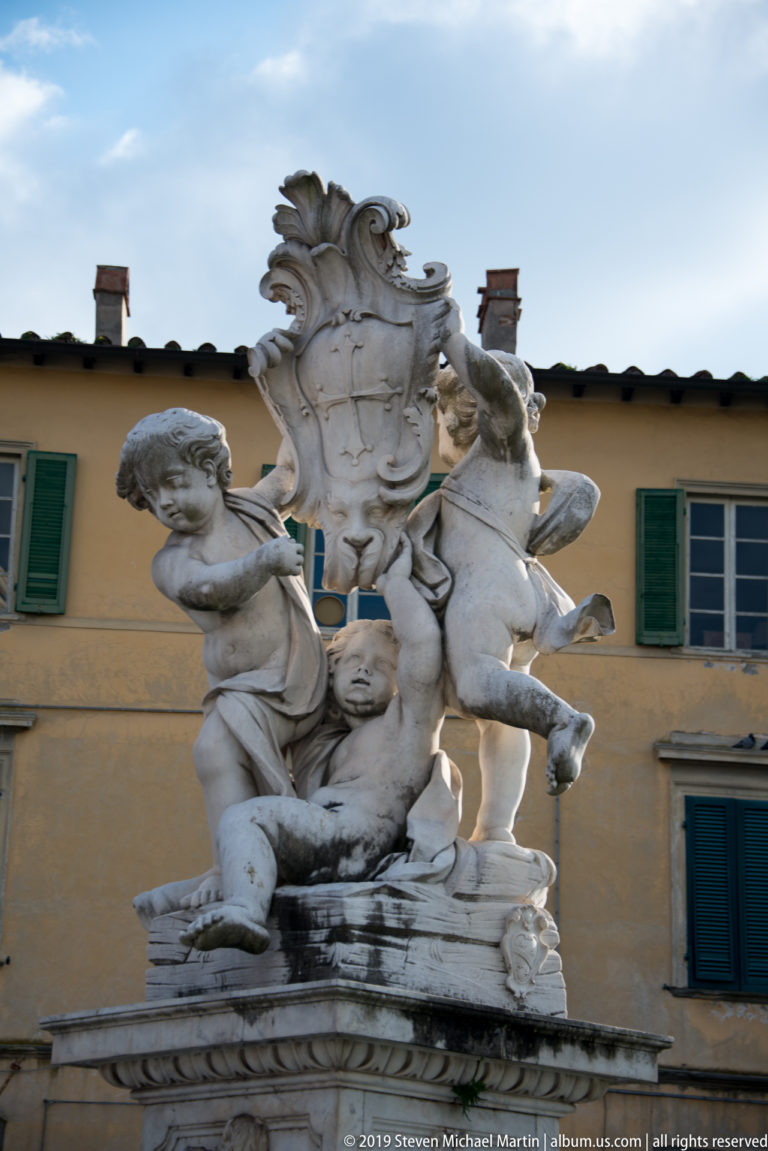 Close view of marble putti and sculptural ornament on the Fontana dei Putti in Pisa’s Piazza del Duomo.