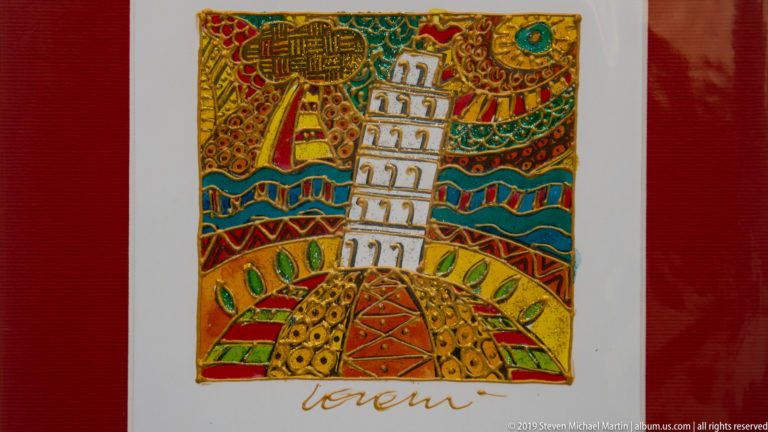 Colorful decorative artwork with a stylized white Leaning Tower of Pisa amid dense red, gold, green, and blue patterns.