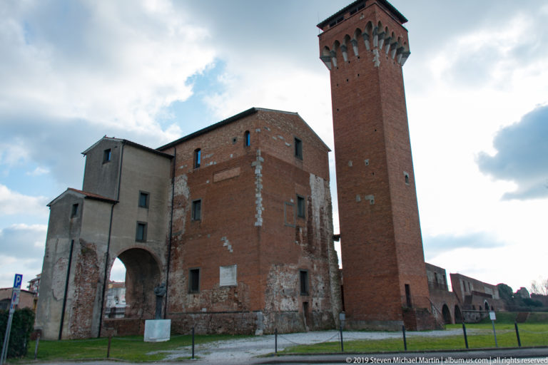 Large arched gateway and Torre Guelfa within the brick-and-stone fortifications of Pisa’s Cittadella Vecchia.