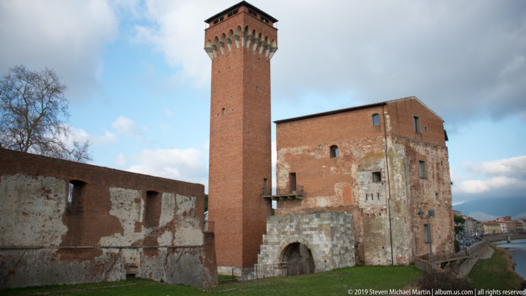 Close low-angle view of the reconstructed Torre Guelfa rising above the masonry of Pisa’s Cittadella Vecchia.