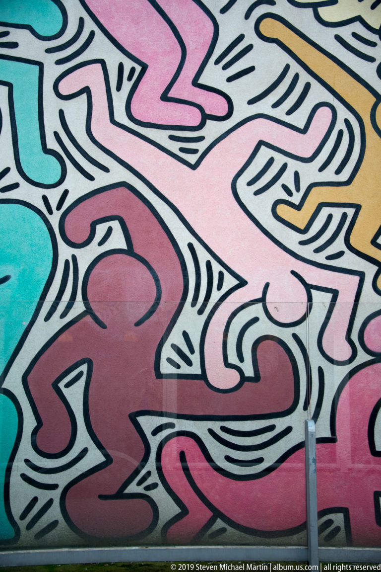 Close mural detail with red and pink outlined figures surrounded by black linear marks and fragments of other colors.