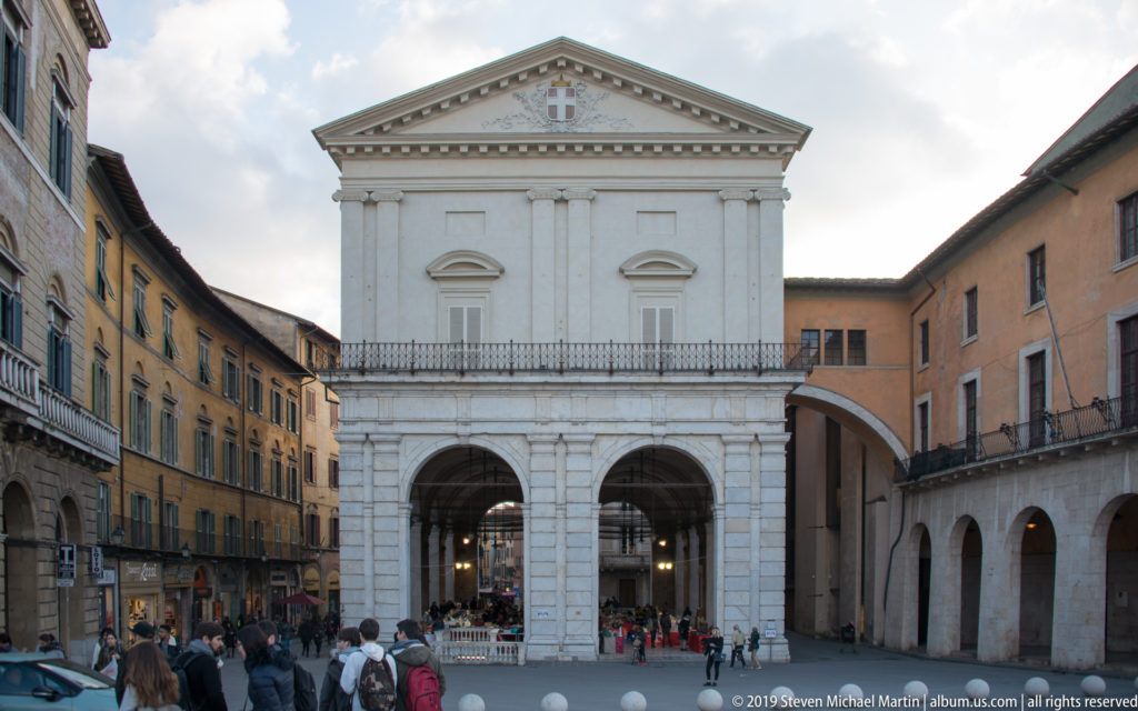 White Logge di Banchi with three large ground-floor arches, upper pediment and pedestrians in the surrounding street.