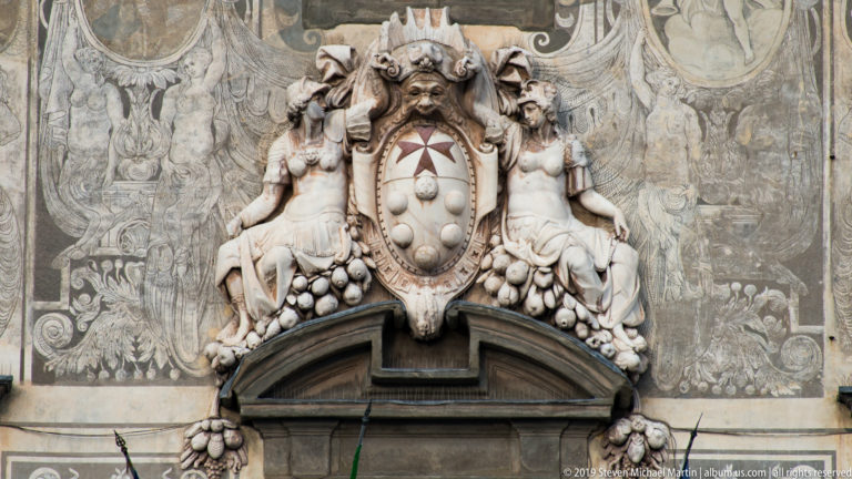 Medici-Stephanian coat of arms flanked by allegorical figures of Religion and Justice on Palazzo della Carovana.