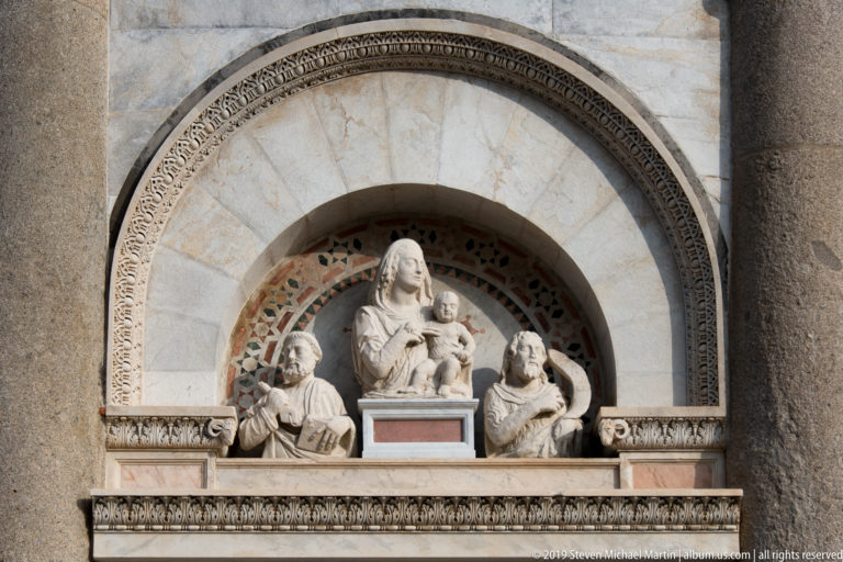Madonna and Child with two flanking figures set in a decorated round-arched niche on the Leaning Tower.