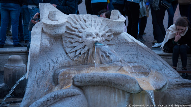 Carved sun-face water spout on the boat-shaped Fontana della Barcaccia at Piazza di Spagna.