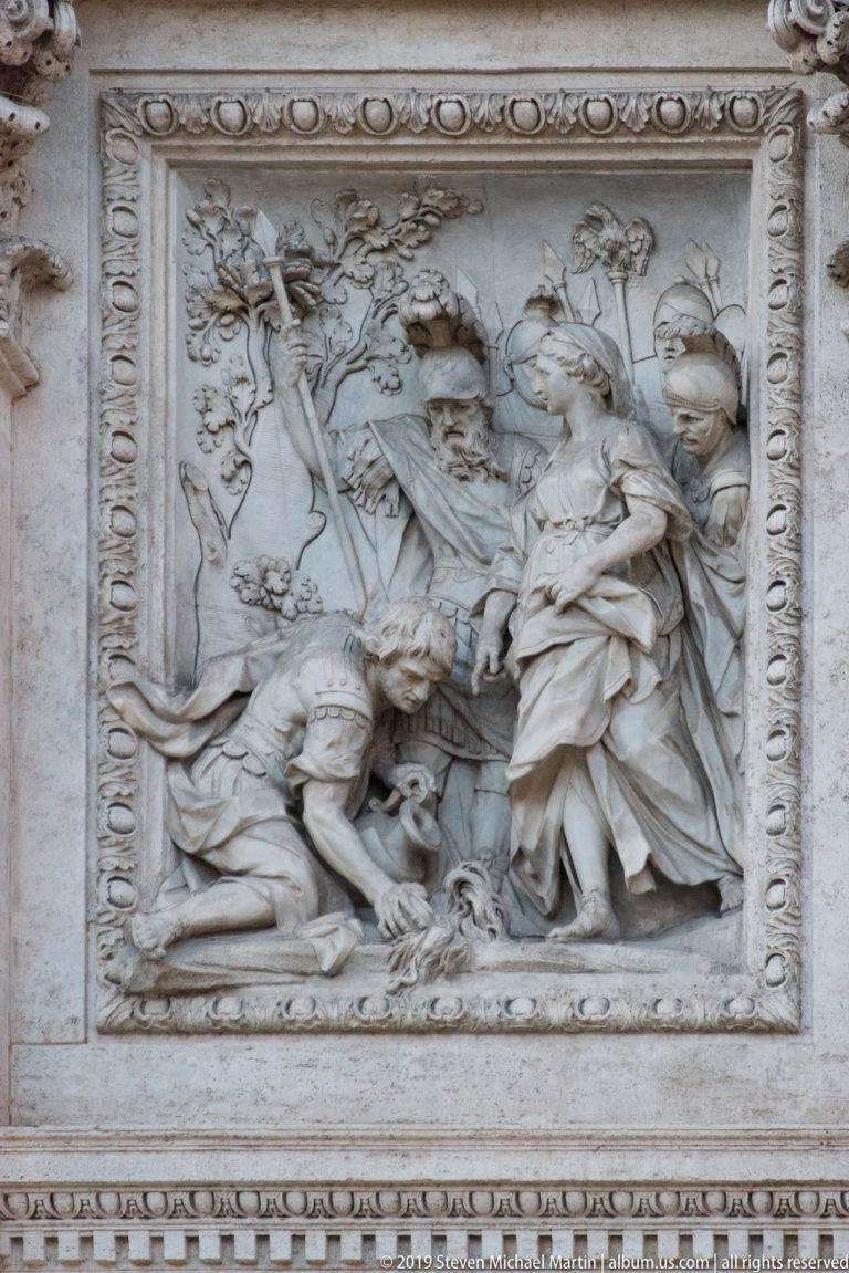 Rectangular carved relief with multiple classical figures in a narrative scene on the Trevi Fountain façade.