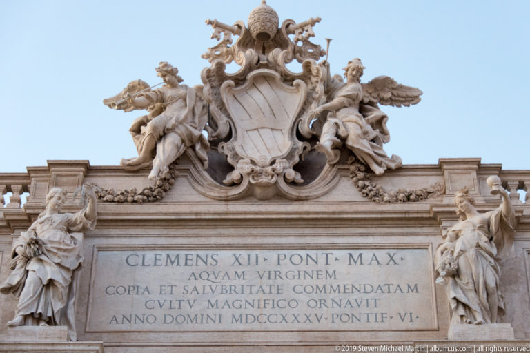Papal coat of arms with tiara, crossed keys, flanking figures, and Latin inscription naming Clement XII.