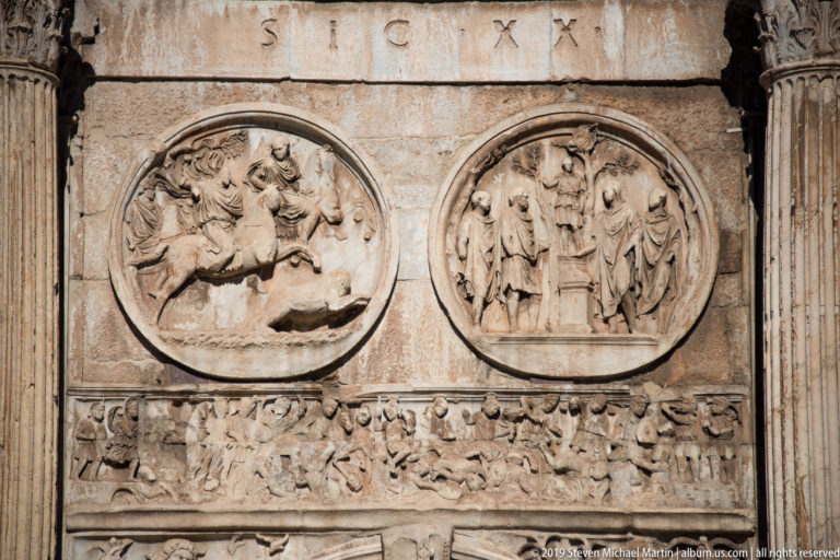 Two circular relief medallions above a densely carved rectangular narrative frieze on the Arch of Constantine.
