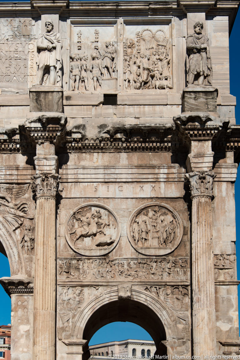 Central arch of the Arch of Constantine beneath columns, roundels, relief panels, captive statues, and attic inscription.