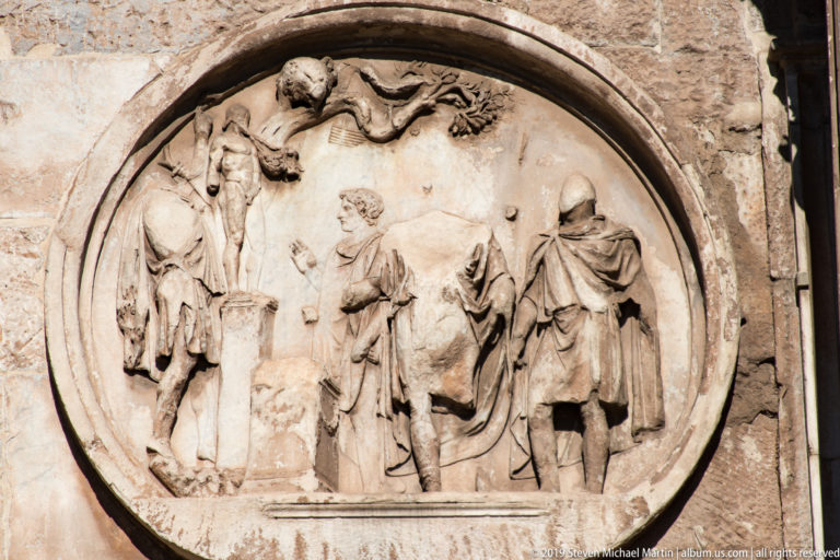 Circular Roman relief showing a group of draped figures gathered around a ritual scene on the Arch of Constantine.