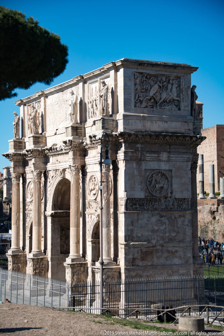 Arch of Constantine with three openings, columns, relief panels, roundels, and inscribed attic beside the Colosseum.
