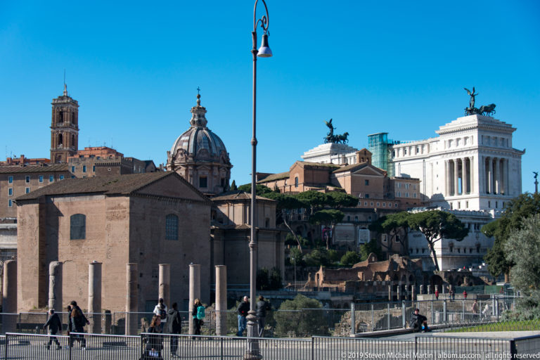 Ancient columns and ruins below Santi Luca e Martina, with the white Vittoriano rising on the skyline.