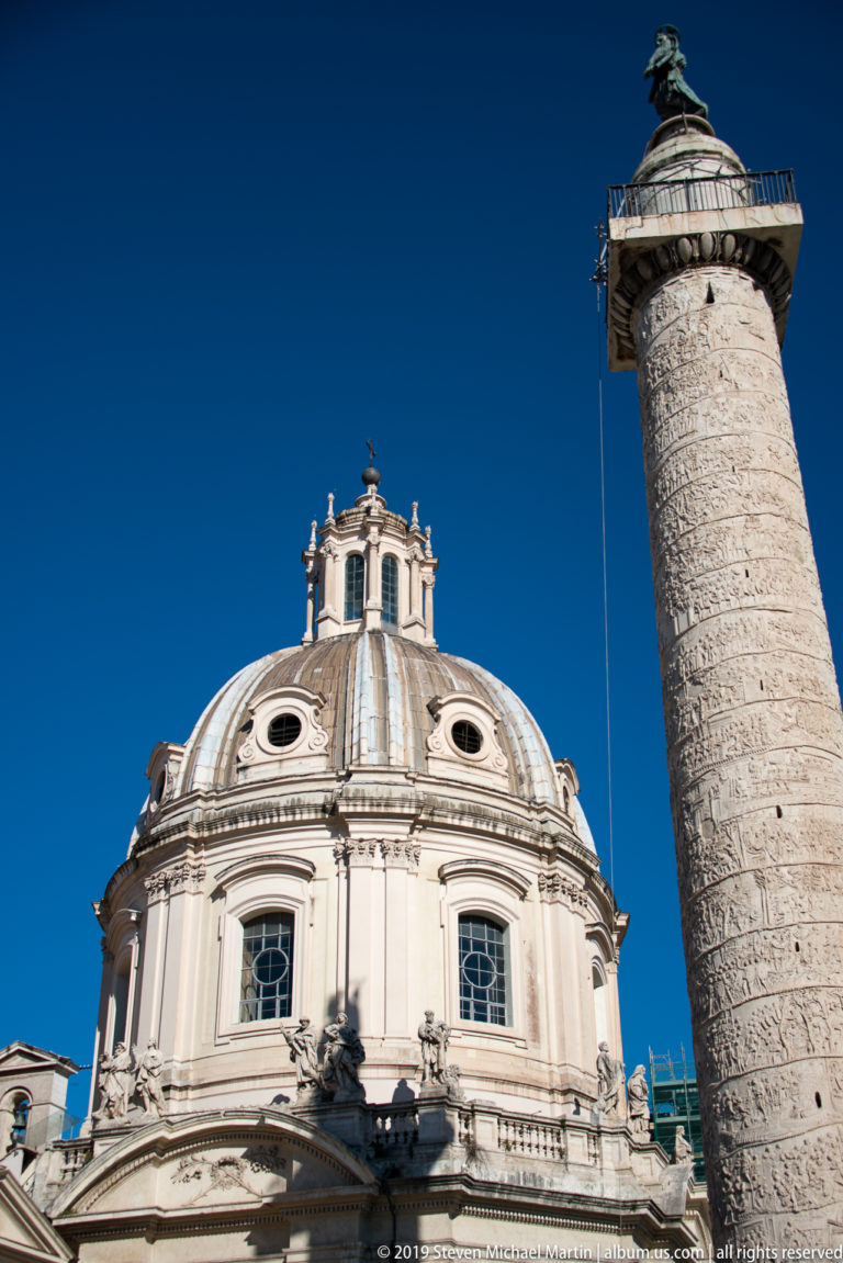Trajan's Column with spiral reliefs and Saint Peter beside the domed church of Santa Maria di Loreto.