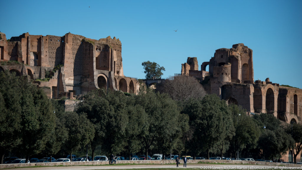 Large brick imperial palace ruins and arches on the Palatine Hill above trees along the Circus Maximus.