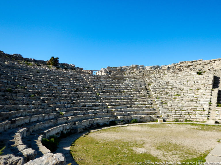 Semicircular stone seating of the ancient theater at Segesta curving around the open orchestra.