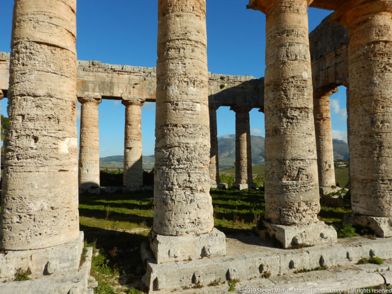Massive weathered Doric columns frame the open interior and distant landscape at the Temple of Segesta.