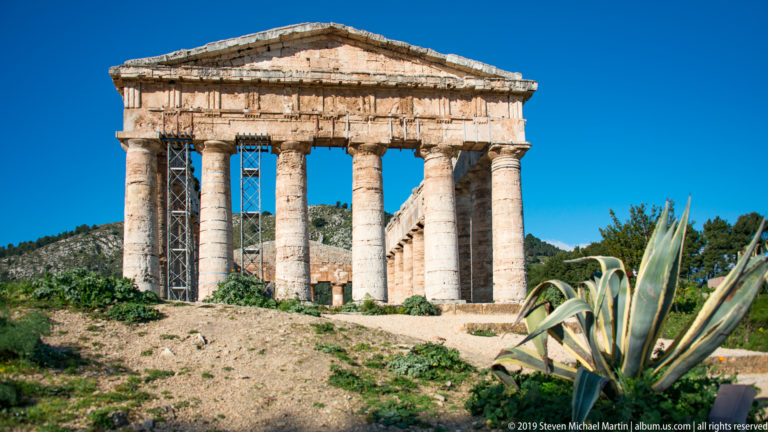 Agave leaves in the foreground with the Doric façade and pediment of the Temple of Segesta beyond.