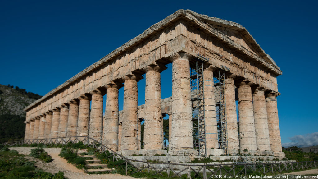 Close oblique view along the corner and long colonnade of Segesta’s Doric temple.