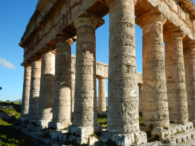 Close interior-side view of massive Doric columns with the opposite colonnade visible through open bays at Segesta.