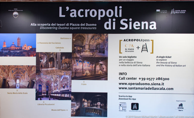 Visitor sign titled “L’acropoli di Siena” with attraction photographs, Italian and English ticket information, and contact details.