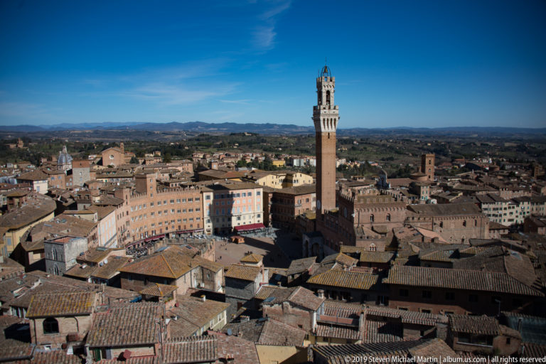 High panoramic view over Siena’s tiled roofs to Piazza del Campo, Palazzo Pubblico, and Torre del Mangia.