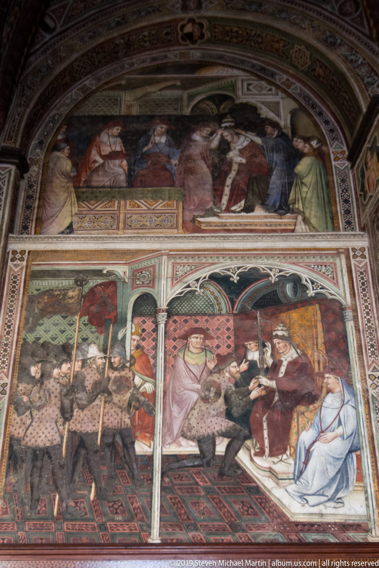 Arched wall covered by two registers of narrative frescoes with richly dressed figures, interiors, and architectural divisions.