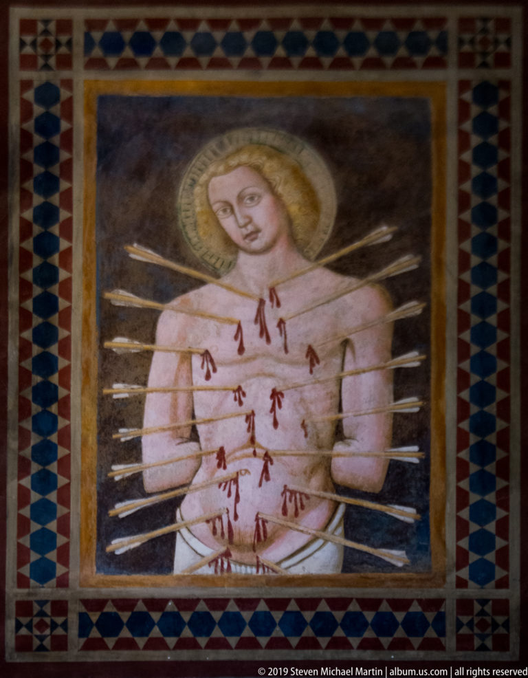 Fresco of haloed Saint Sebastian with numerous arrows piercing his bare torso and arms, framed by a geometric border.