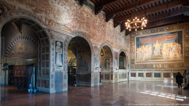 Sala del Mappamondo with Simone Martini’s Maestà on the end wall, equestrian frescoes along the side, and timber ceiling above.