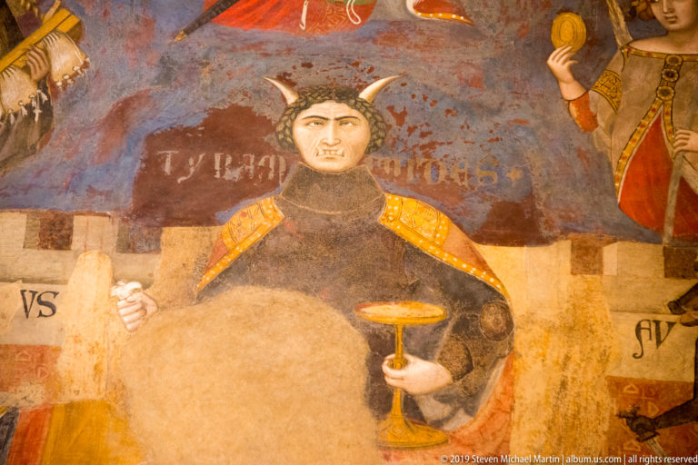 Horned personification of Tyranny in dark robes holding symbolic objects in Ambrogio Lorenzetti’s Bad Government fresco.