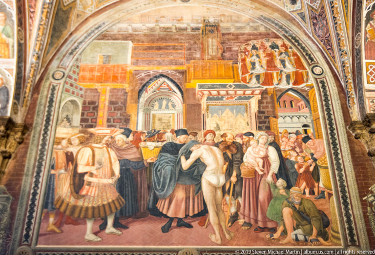 Fresco of officials and onlookers surrounding a nude male figure before brick buildings, towers, and elevated spectators.
