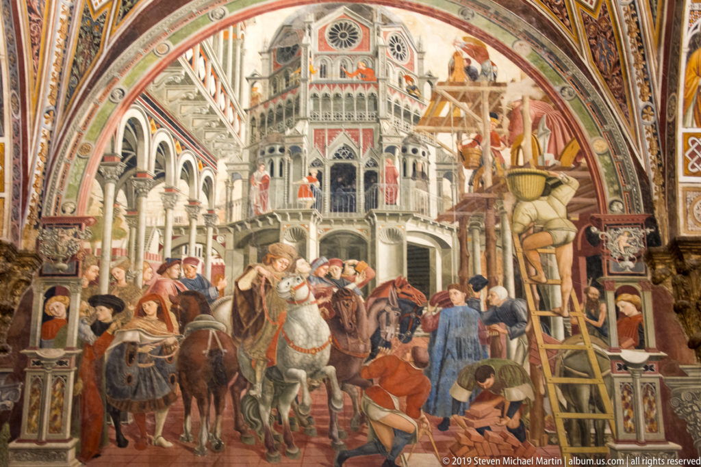 Fresco of mounted figures and laborers at a construction site with ladders, scaffolding, materials, and a monumental building.
