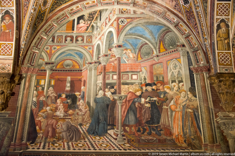 Fresco of seated recipients, robed officials, and attendants gathered inside an ornate painted hall with columns and patterned pavement.