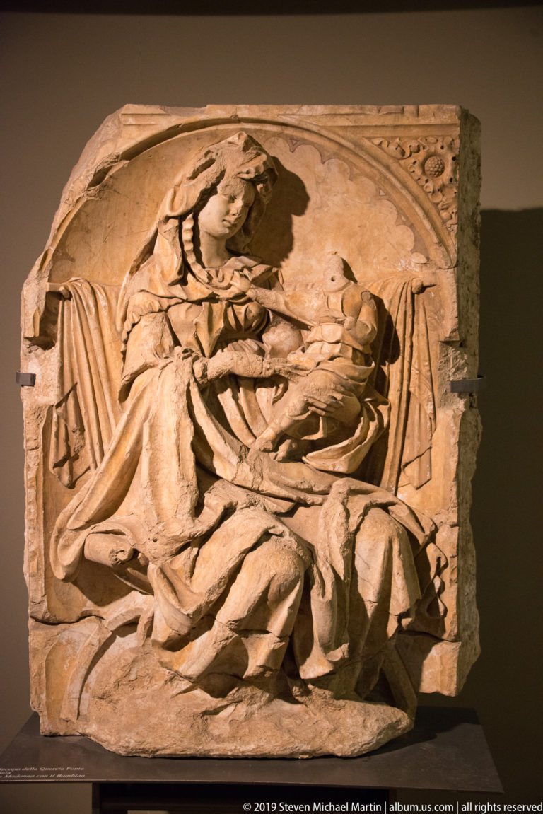 Fragmentary stone relief of the Madonna and Child with broken edges and heavily worn drapery and faces.