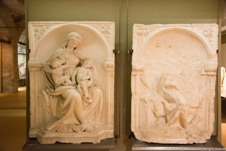 Two arched stone reliefs of the Madonna and Child, one well preserved and the other heavily worn.
